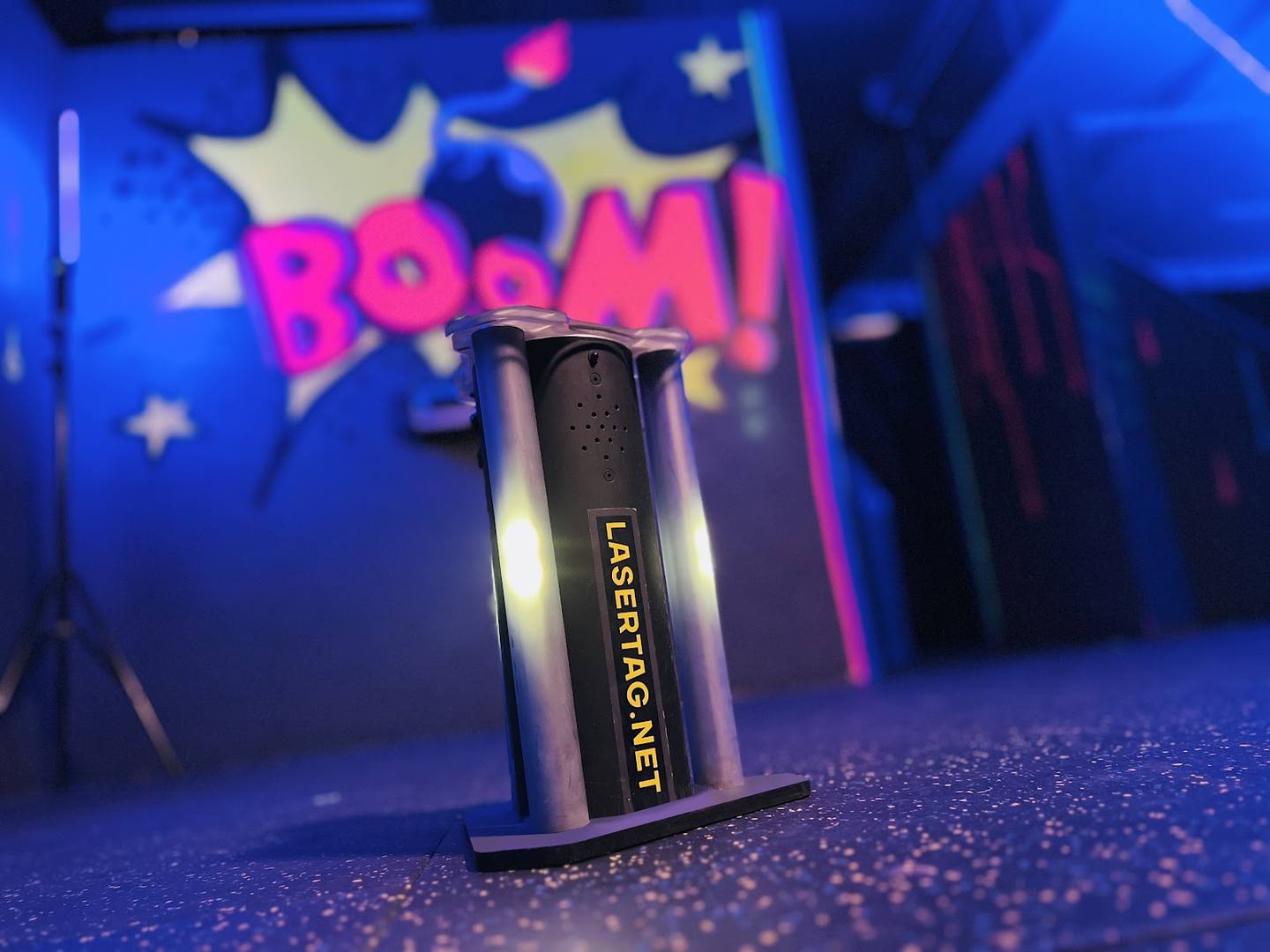 Close-up of a branded energy drink can with neon signage blurred in background at an entertainment venue