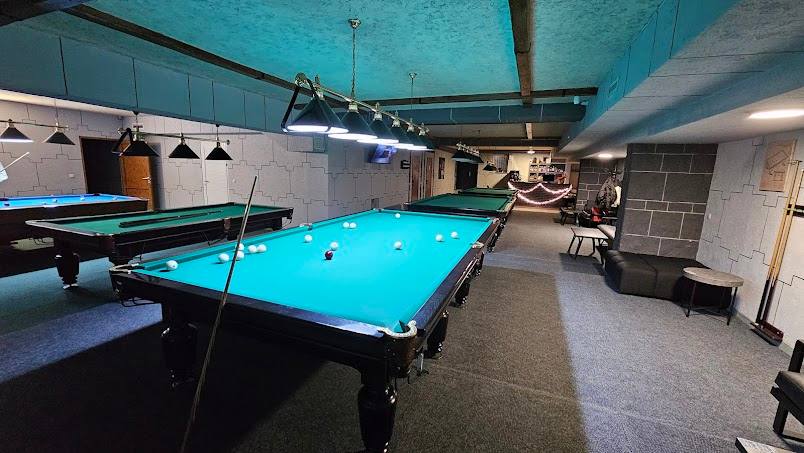 Bright blue billiard table in modern recreation room with pool tables and ambient lighting