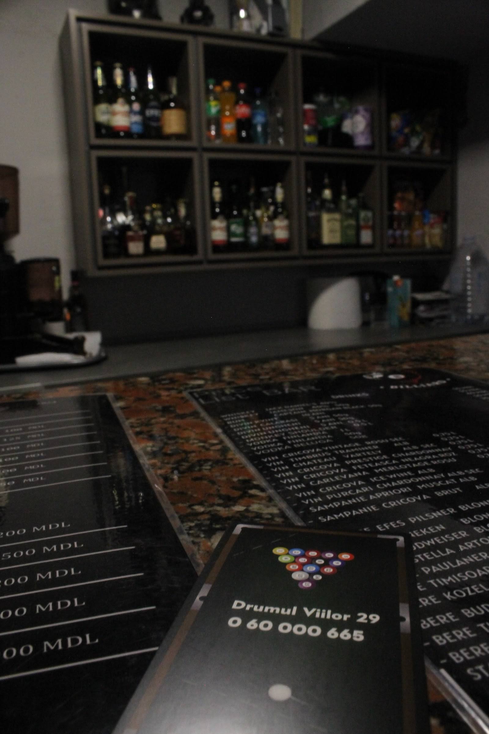 Bar counter with menu cards and backlit bottle display wall