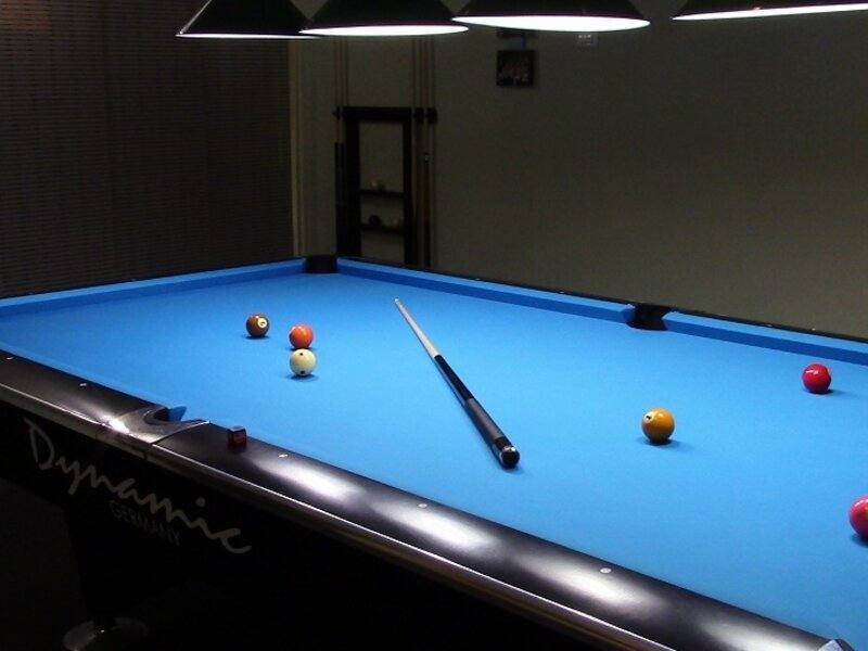 Billiard table with pool balls and cue in modern venue