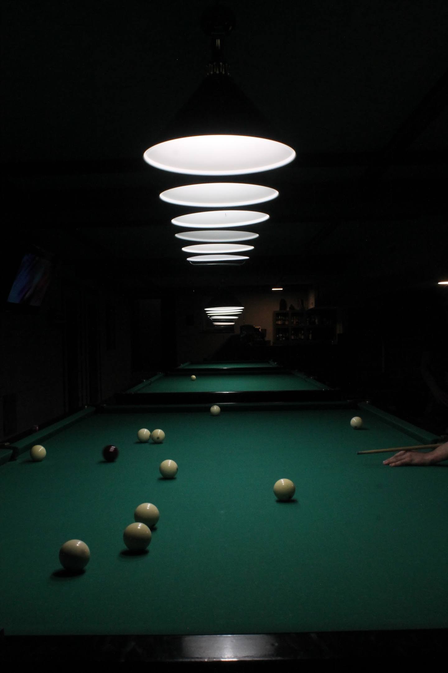 Pool table with scattered balls under dramatic ring lighting