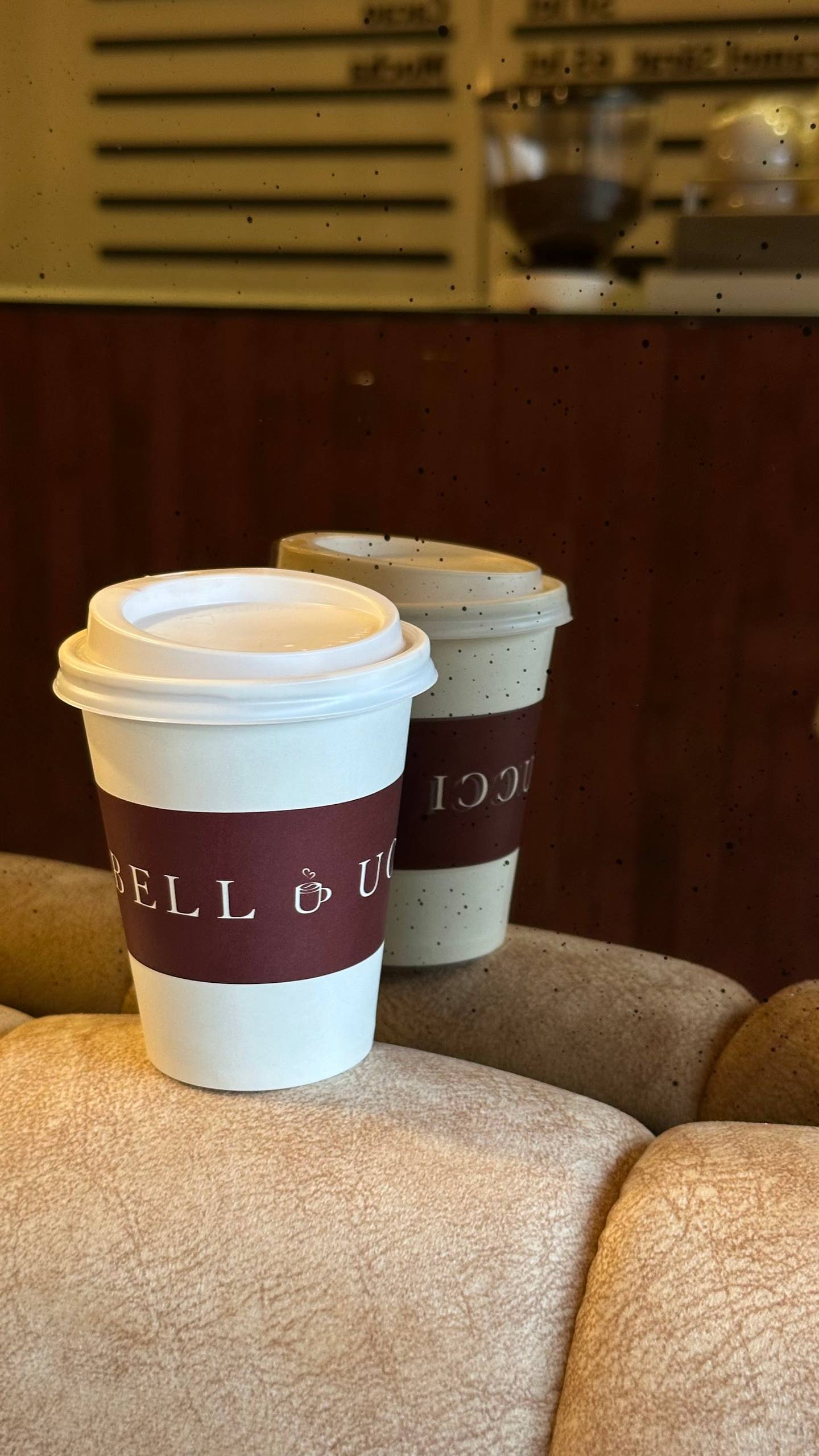Coffee cups on beige seating with blurred cafe counter background