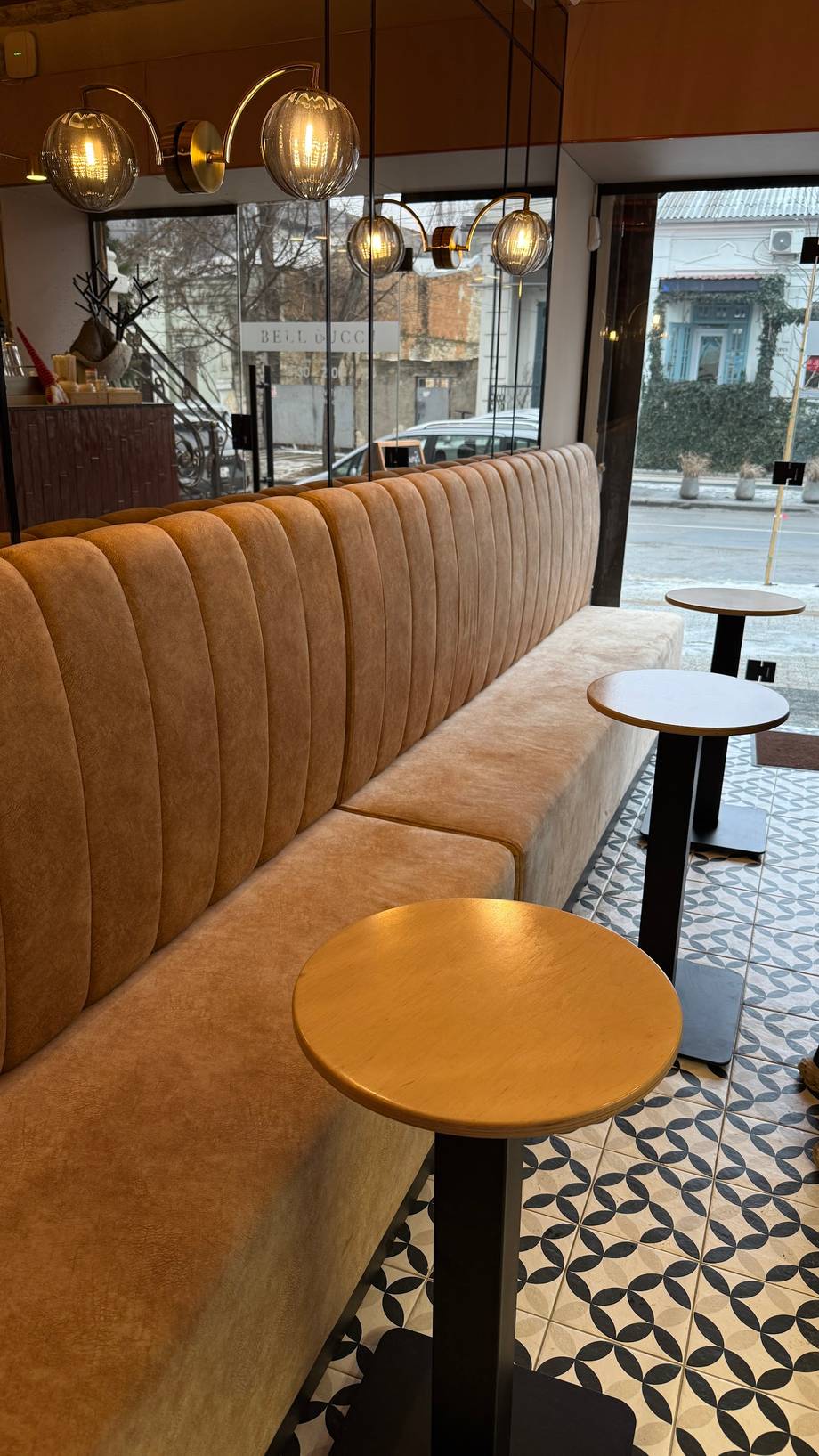 Modern cafe interior with ribbed leather banquette seating, pendant lighting, and street-facing windows