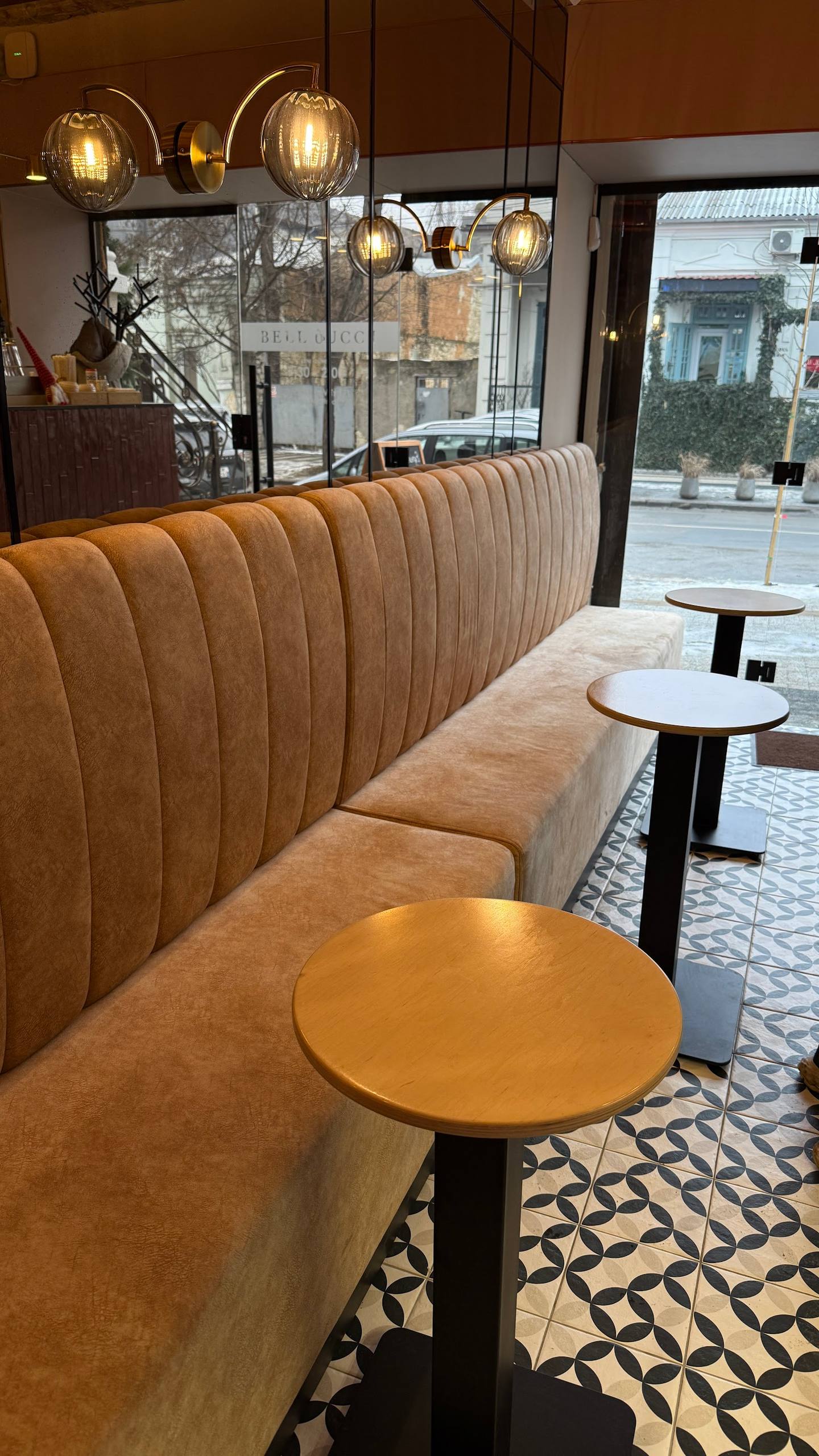 Modern cafe interior with ribbed leather banquette seating, pendant lighting, and street-facing windows