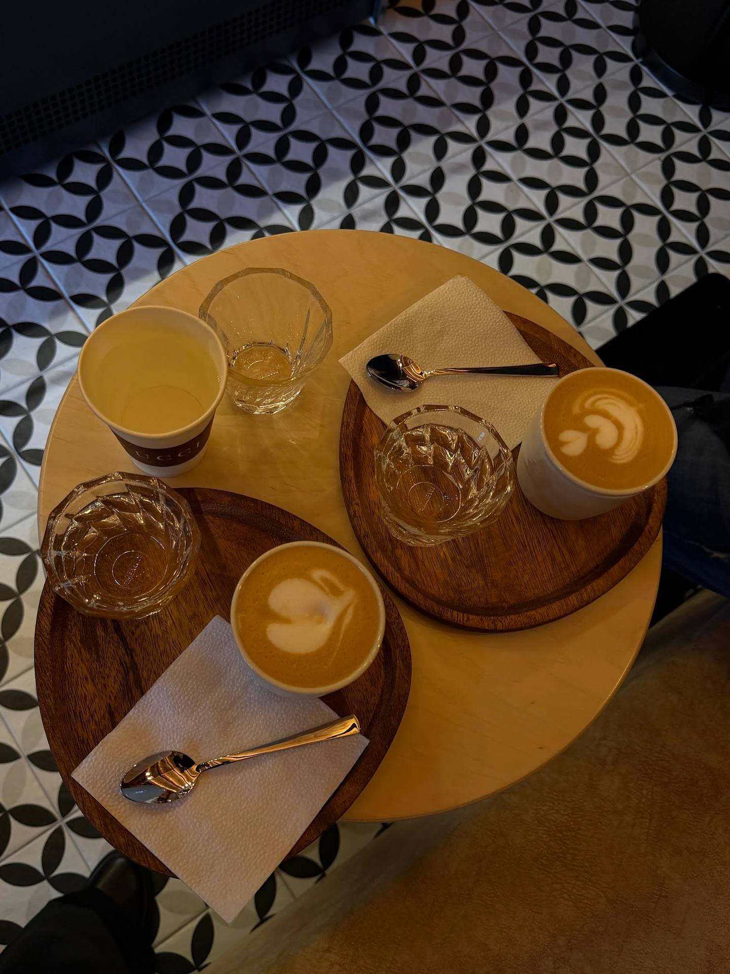 Overhead view of cappuccino and espresso drinks with latte art on wooden coasters