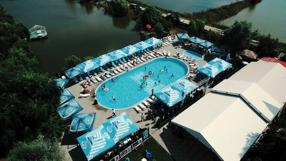 Aerial view of swimming pool complex with loungers and riverside setting