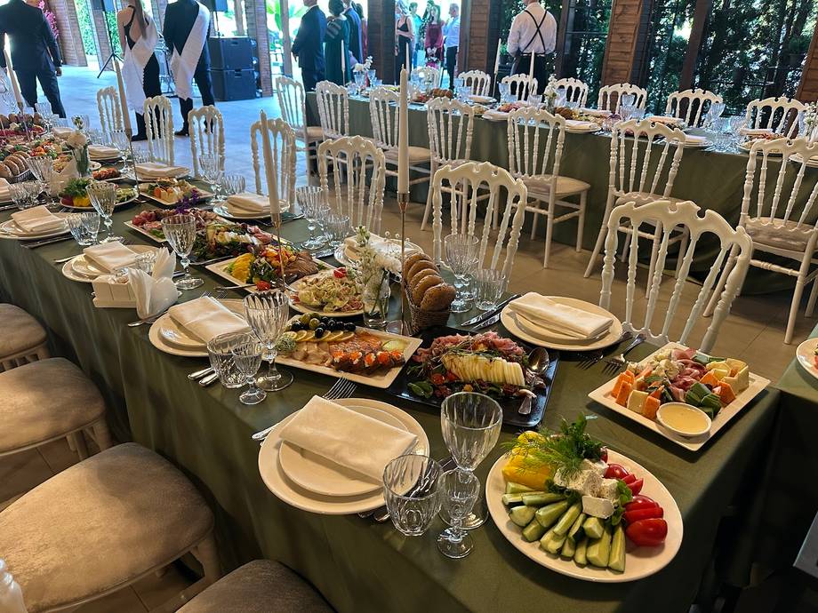 Outdoor reception setup with plated food service and elegant table arrangements under tent
