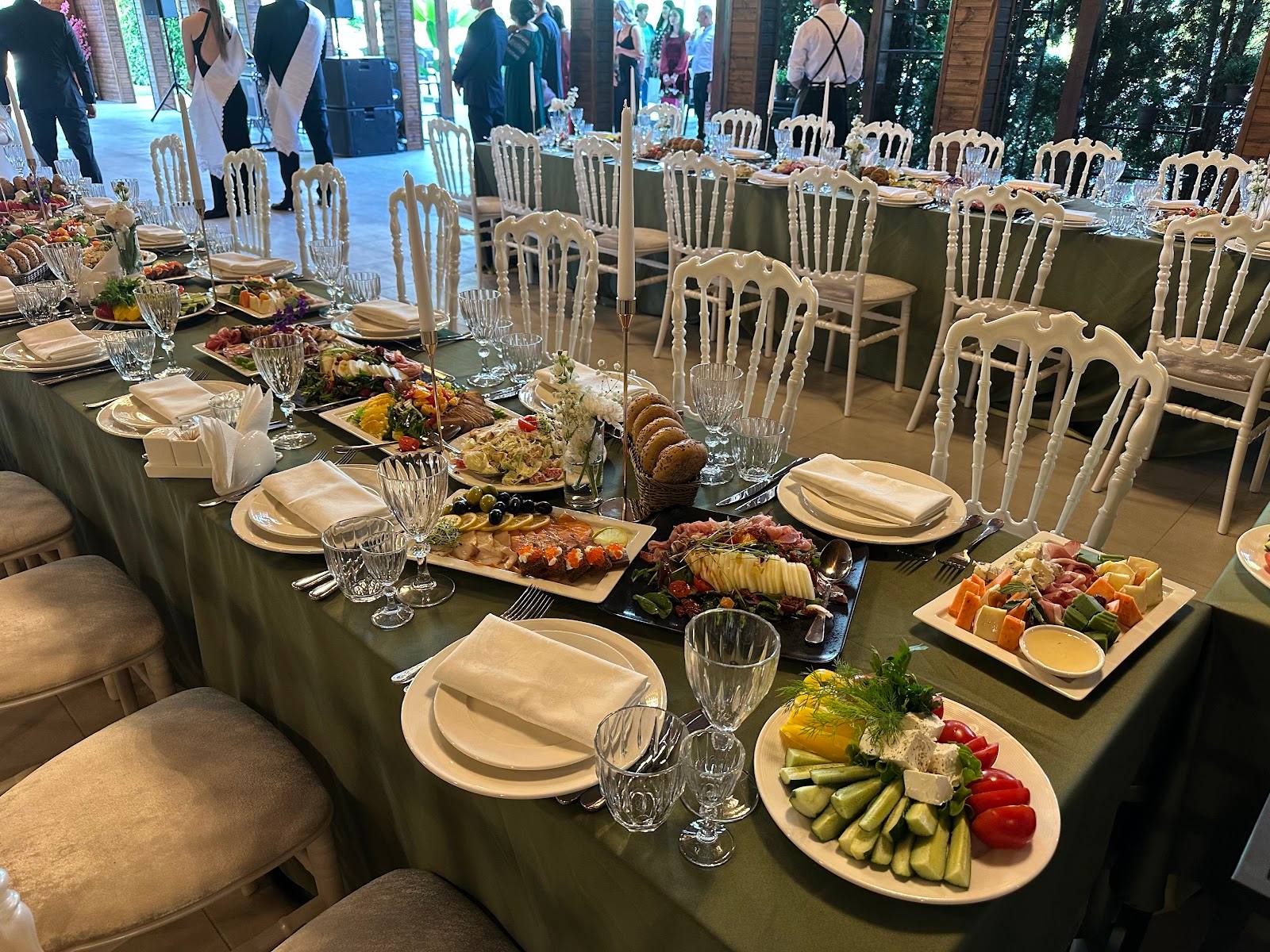 Outdoor reception setup with plated food service and elegant table arrangements under tent