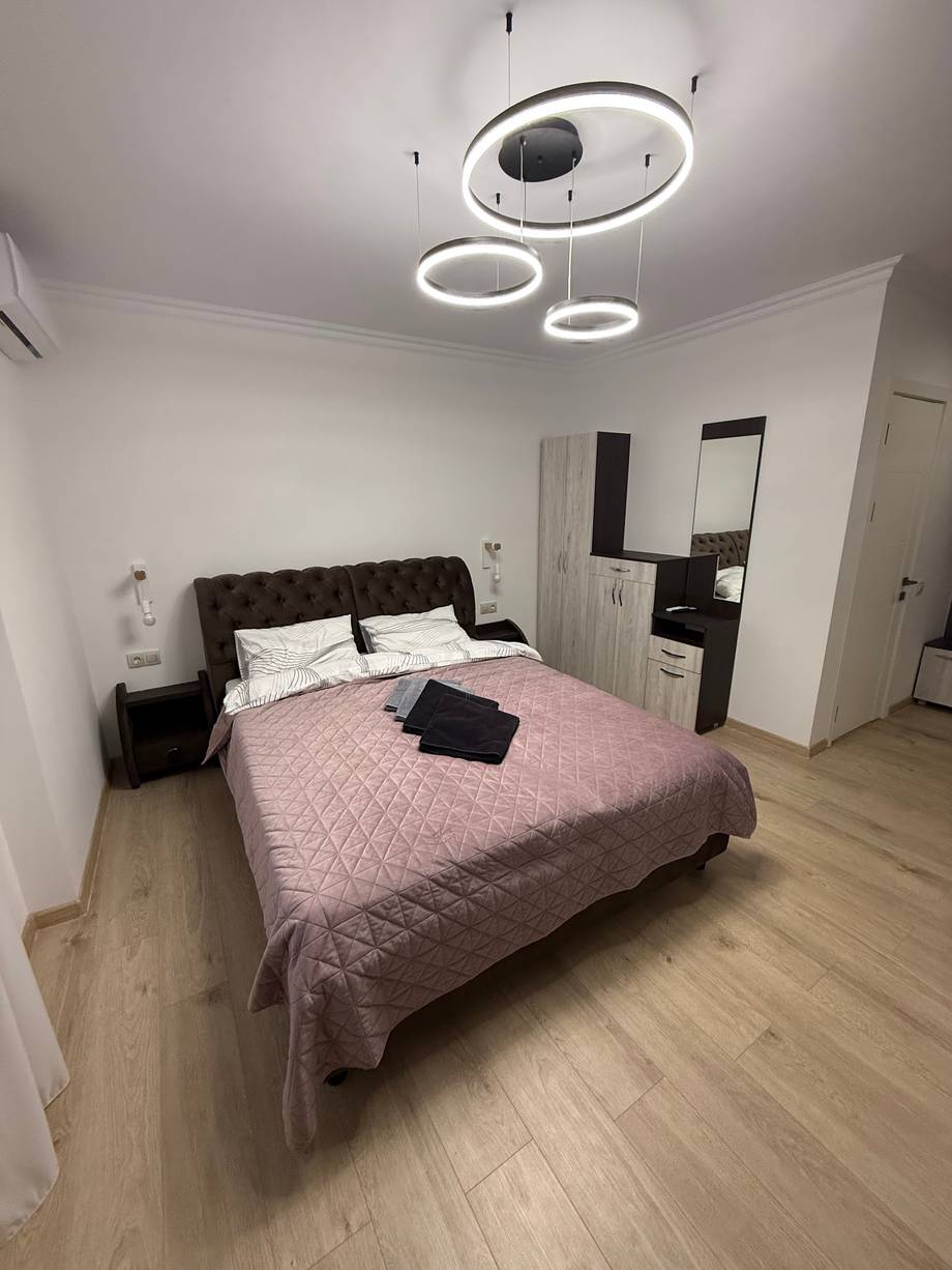 Modern bedroom with queen bed, contemporary LED ceiling lights, and minimalist furnishings