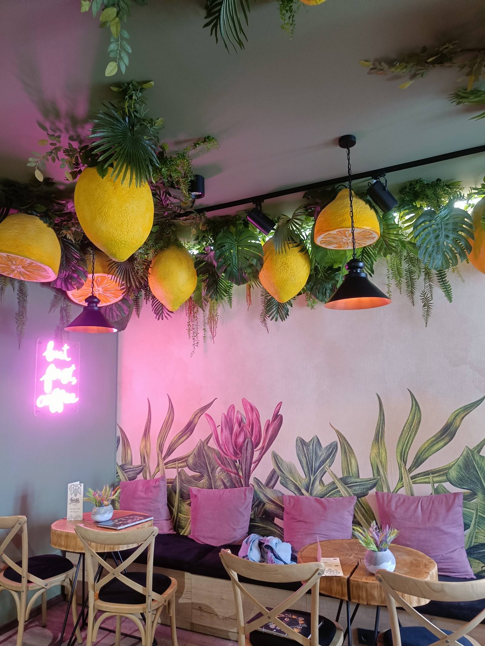Tropical-themed café interior with neon accents, hanging fruit décor, and botanical plants