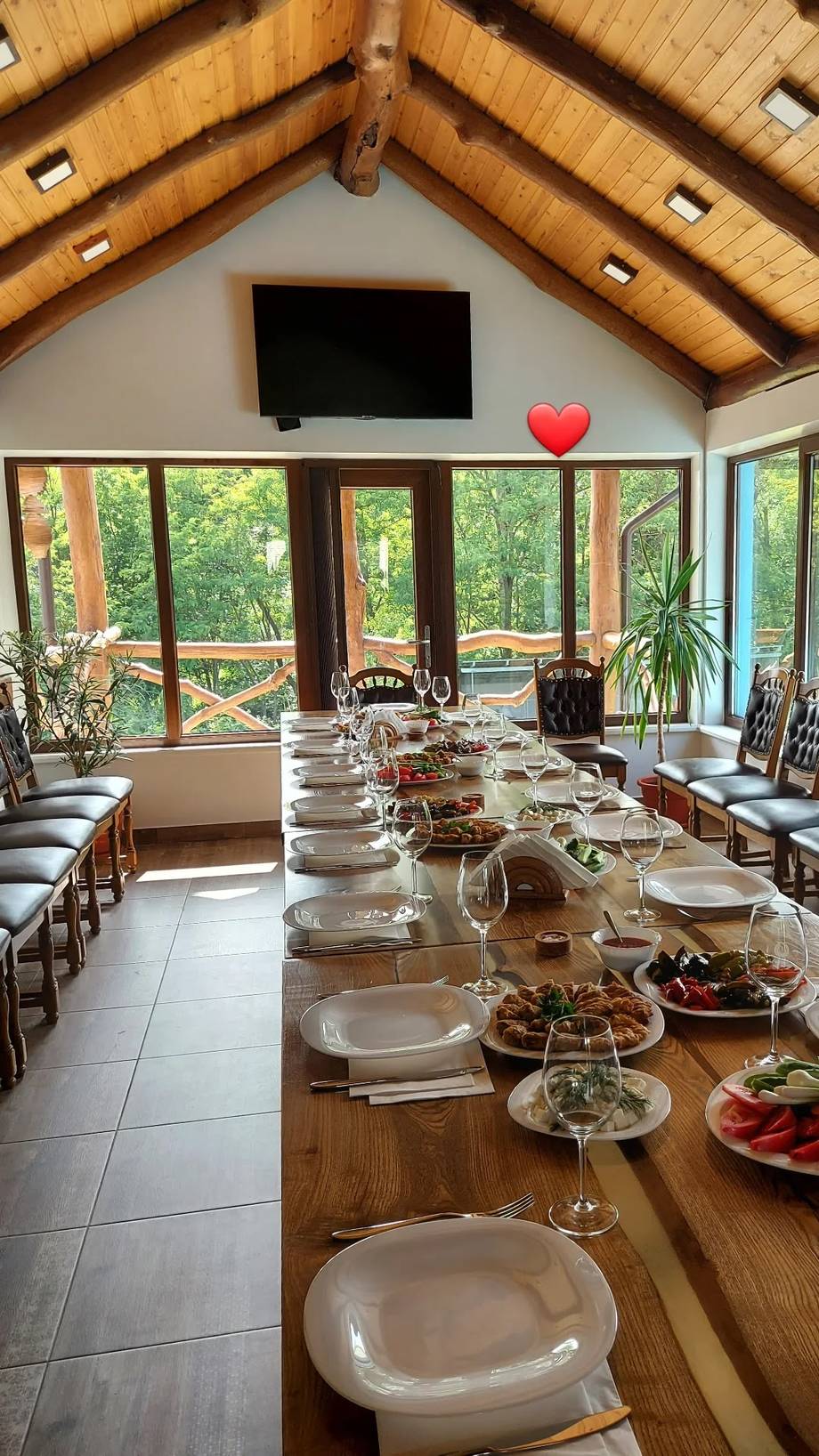 Elegant dining room with vaulted wooden ceiling and large windows overlooking gardens