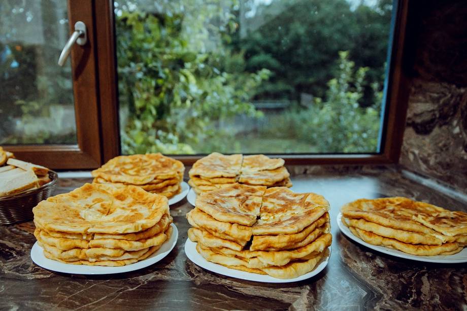Golden pancakes stacked on white plates with countryside view through large windows