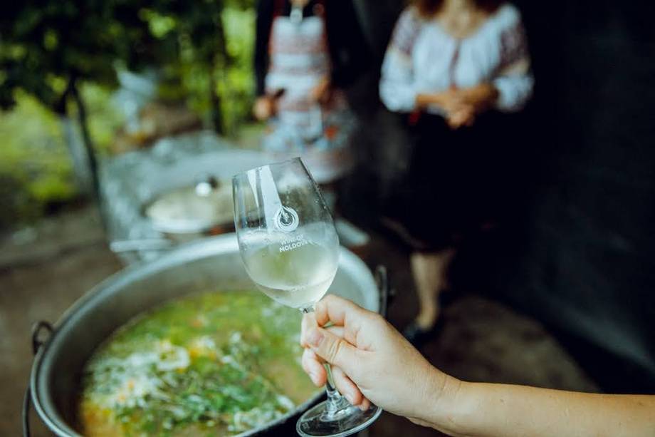 Hand holding a wine glass with outdoor food service in background