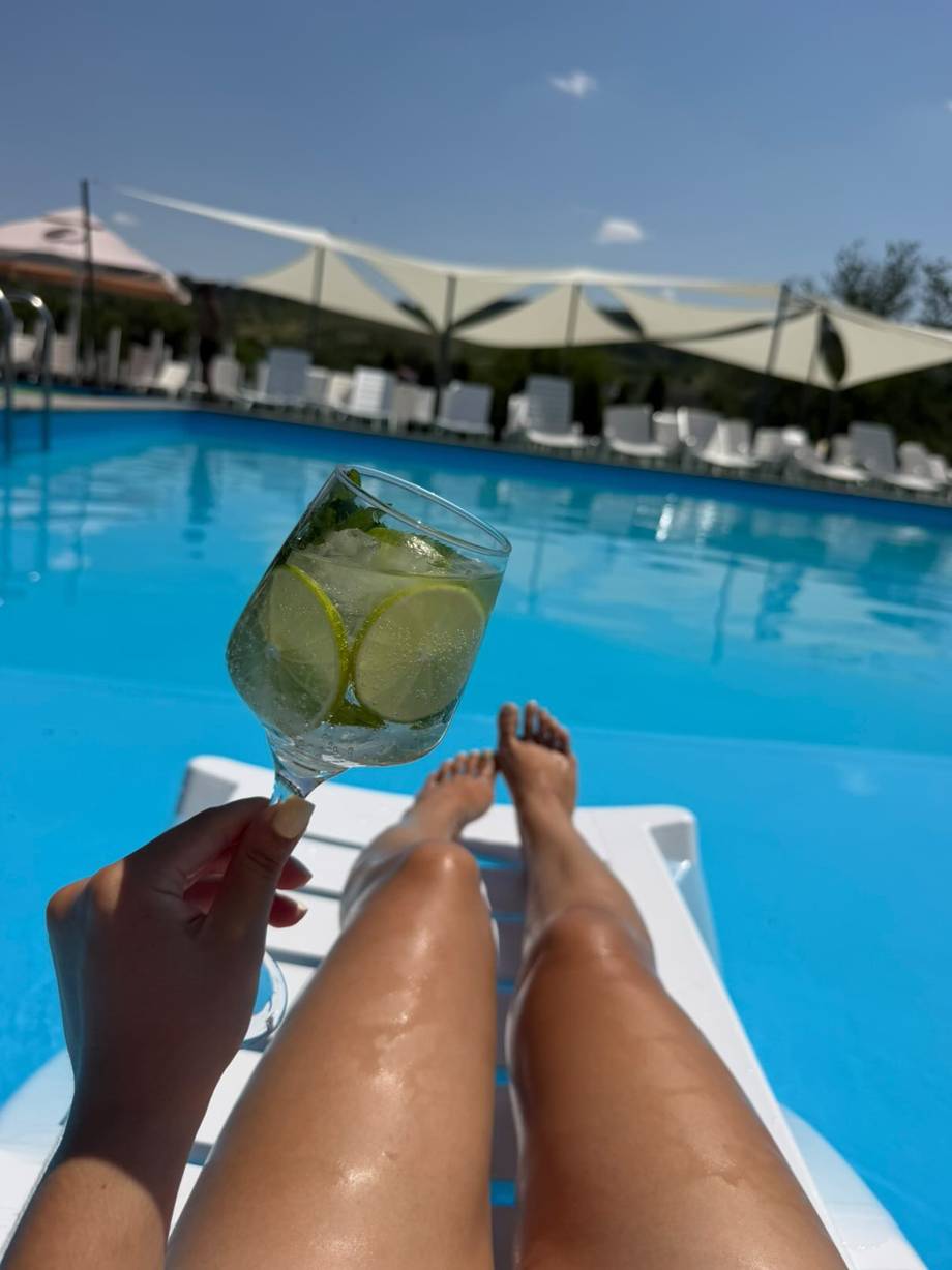 Refreshing cocktail by the pool with shaded lounging area and blue water