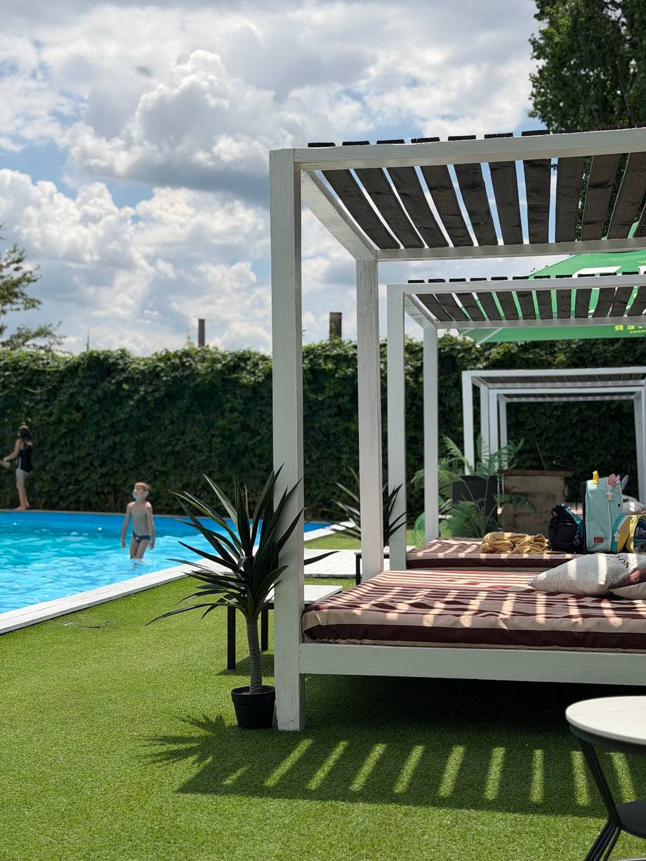 Luxury outdoor terrace with pergola, pool, and manicured lawn