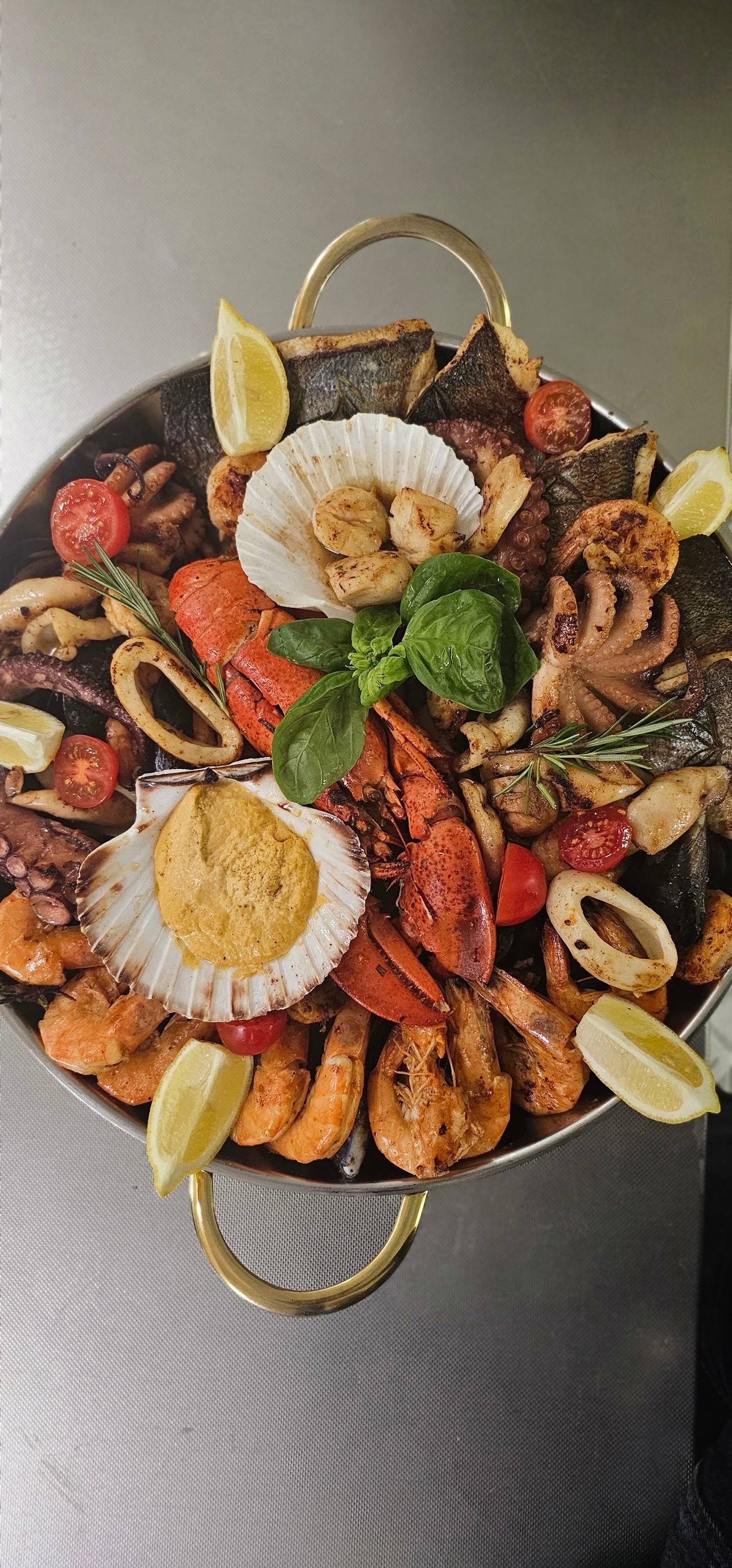 Seafood paella platter with shrimp, clams, mussels, chorizo and lime garnish