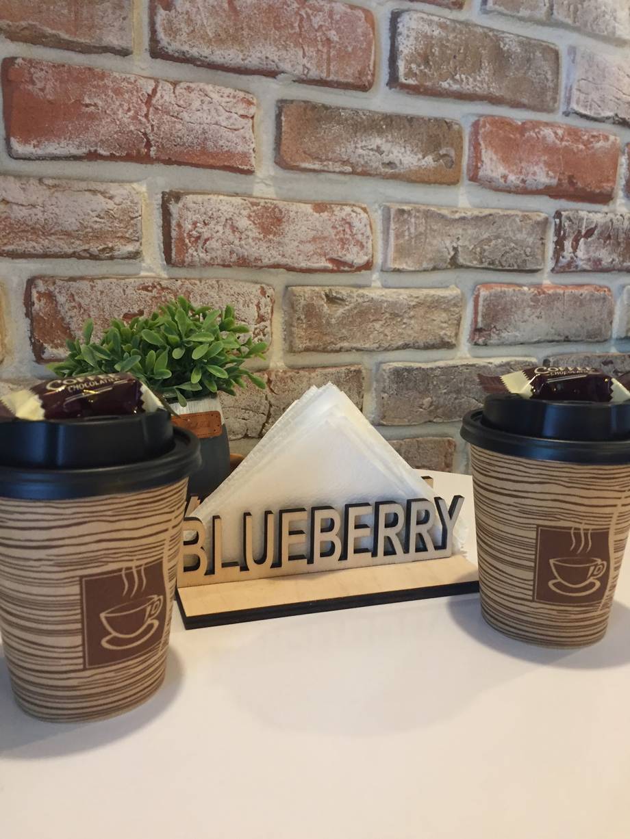Coffee cups and blueberry sign on counter with brick wall backdrop