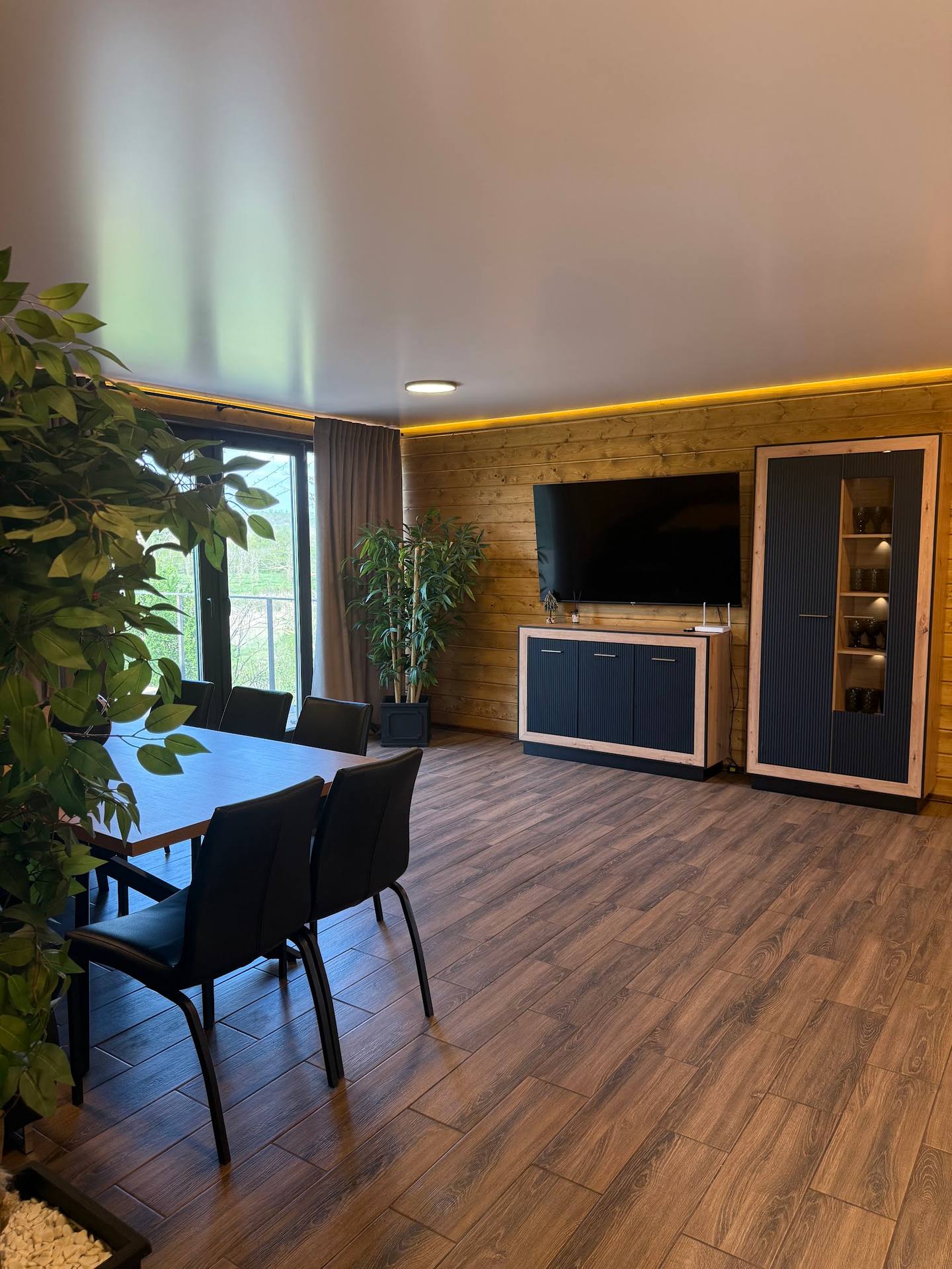 Modern interior with wooden wall accents, dining area, and ambient lighting