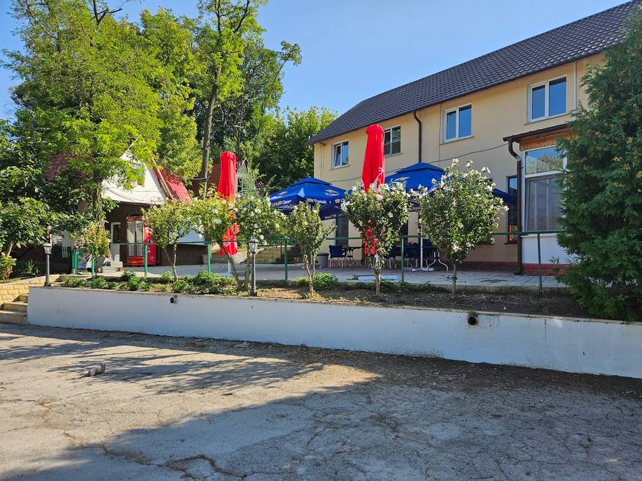Rustic farmhouse venue with yellow facade, red umbrellas, and landscaped entrance courtyard