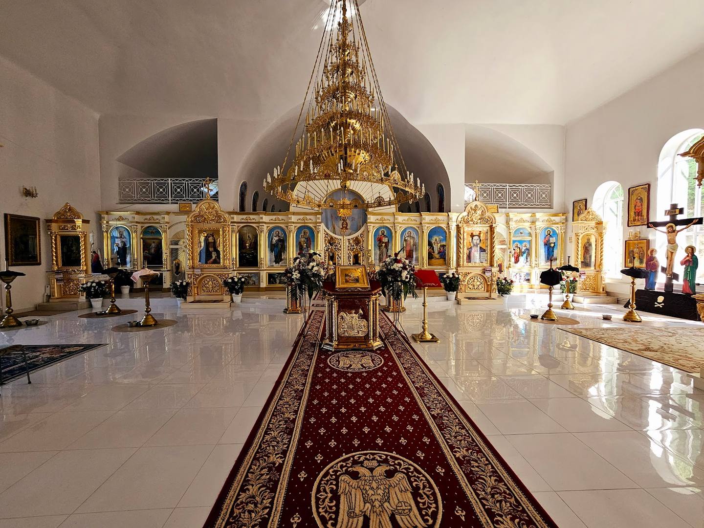 Orthodox monastery interior with iconostasis, chandeliers, and altar nave