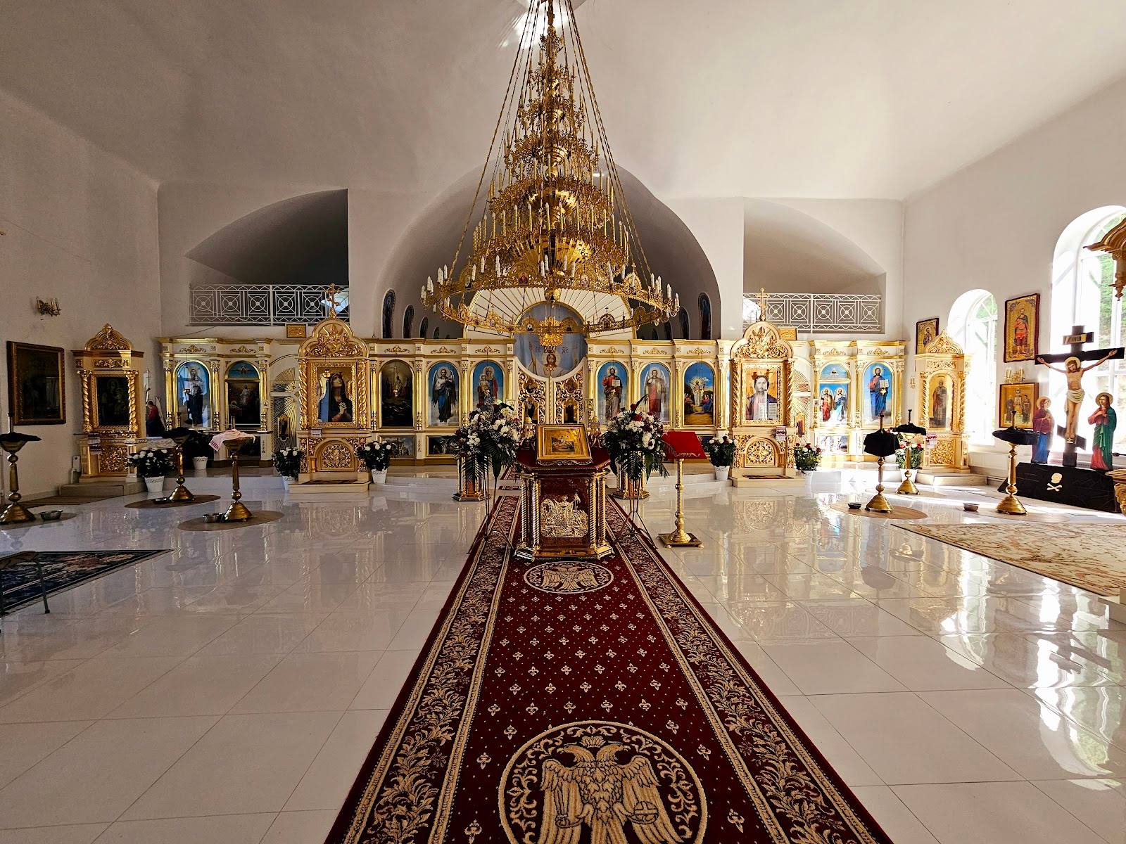 Orthodox monastery interior with iconostasis, chandeliers, and altar nave
