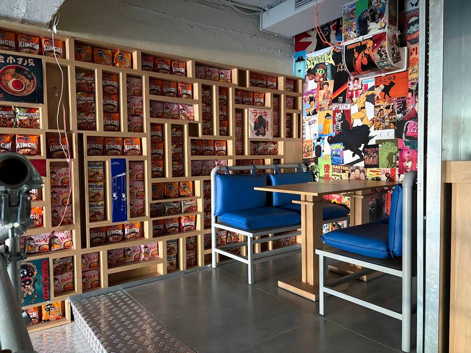 Creative workshop or gallery space with wooden display shelves, blue seating, and eclectic wall art