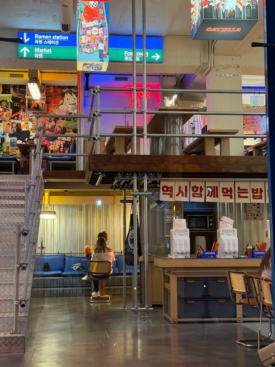 Modern Korean café interior with neon signage, counter service area, and colorful retail display