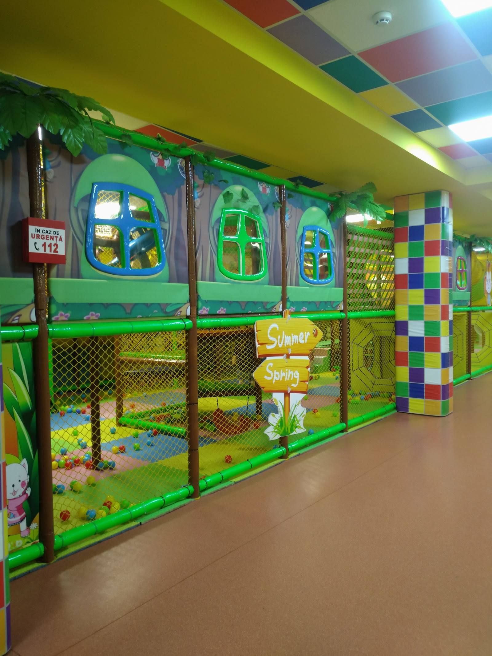 Bright children's play area with green climbing structures and colorful ball pits