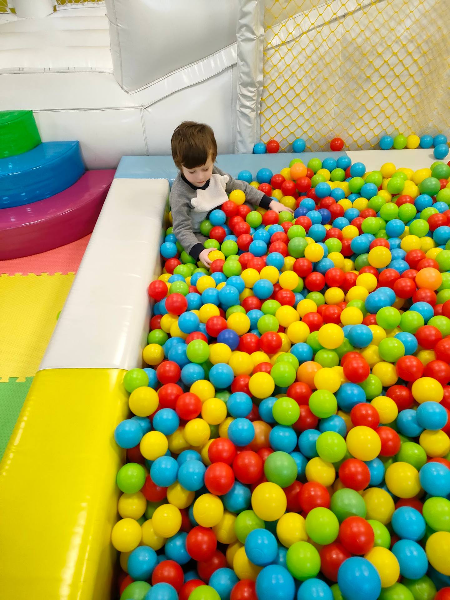 Child playing in colorful ball pit at indoor play center