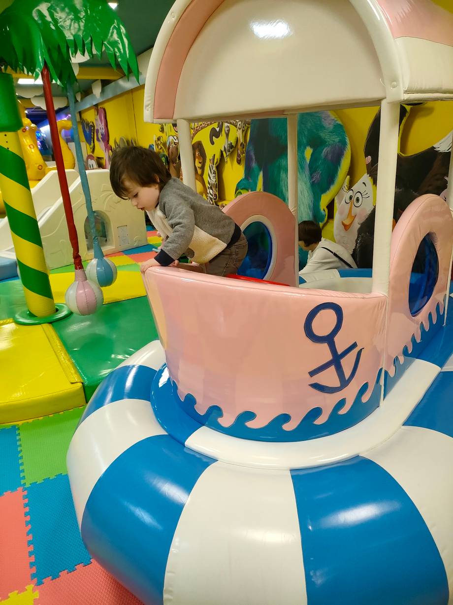 Child playing in nautical-themed ride at indoor play center