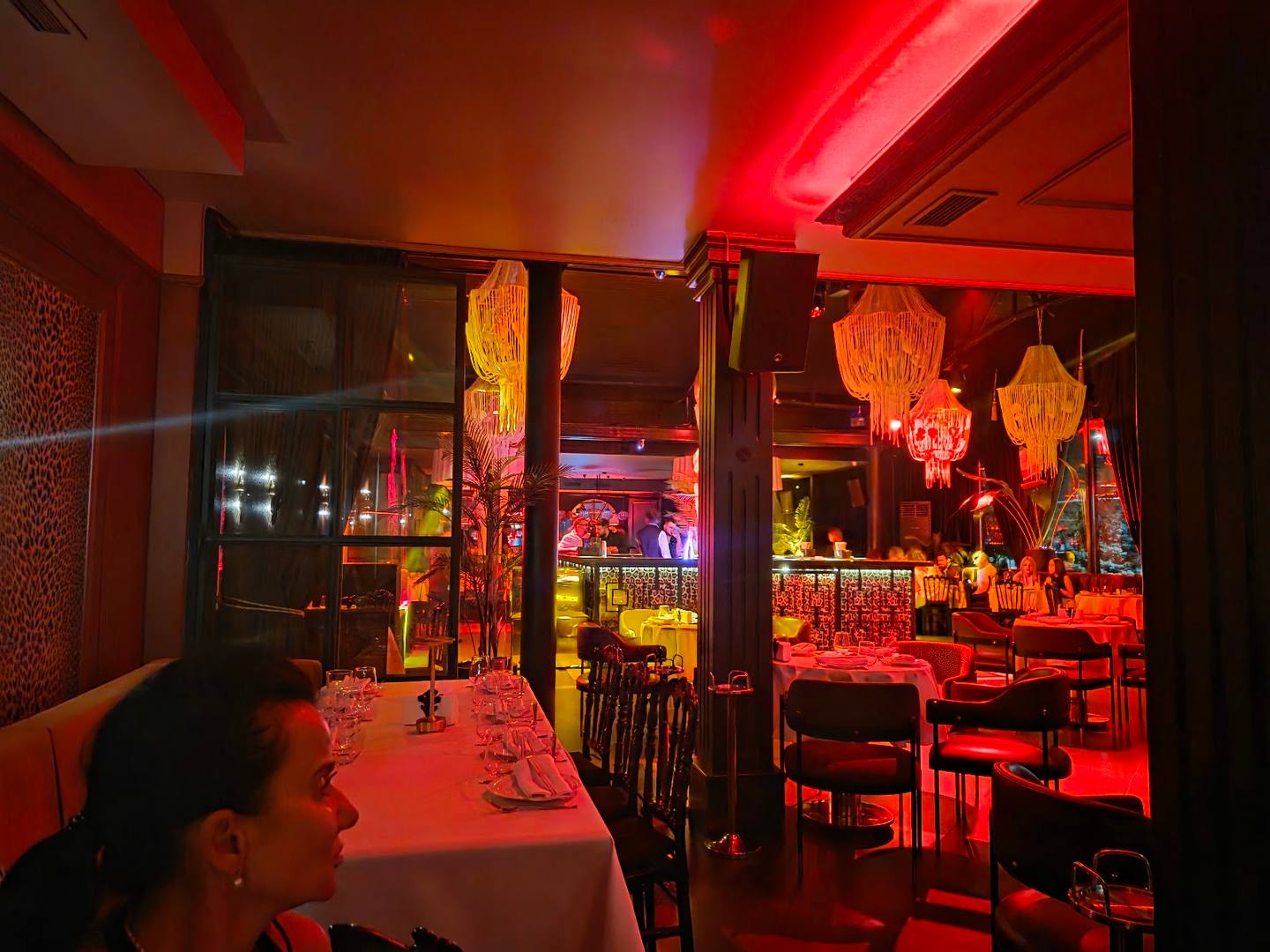 Red ambient lighting and Asian decor in restaurant dining room with artistic lantern installations