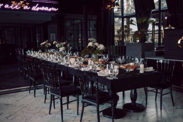 Long banquet table with place settings and floral centerpieces in evening light