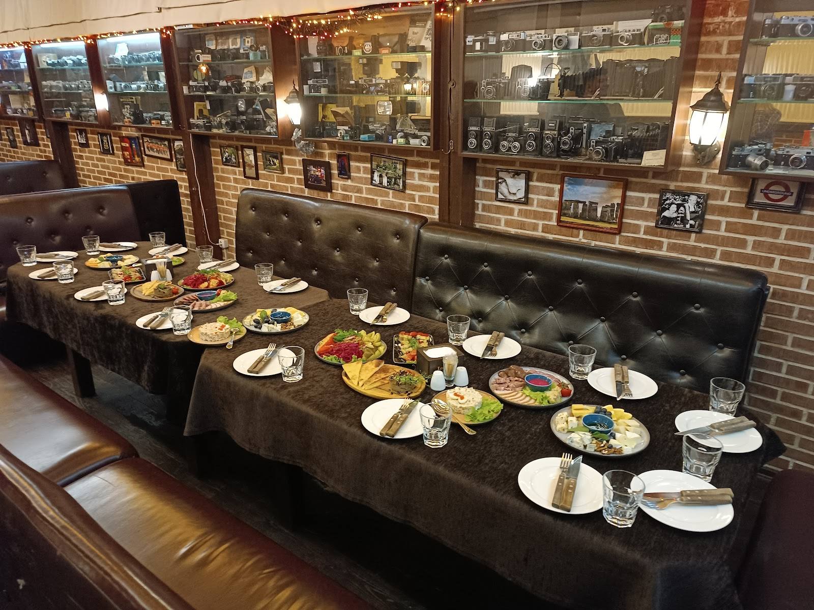 Plated dishes arranged on black leather booth seating with brick wall and display cases