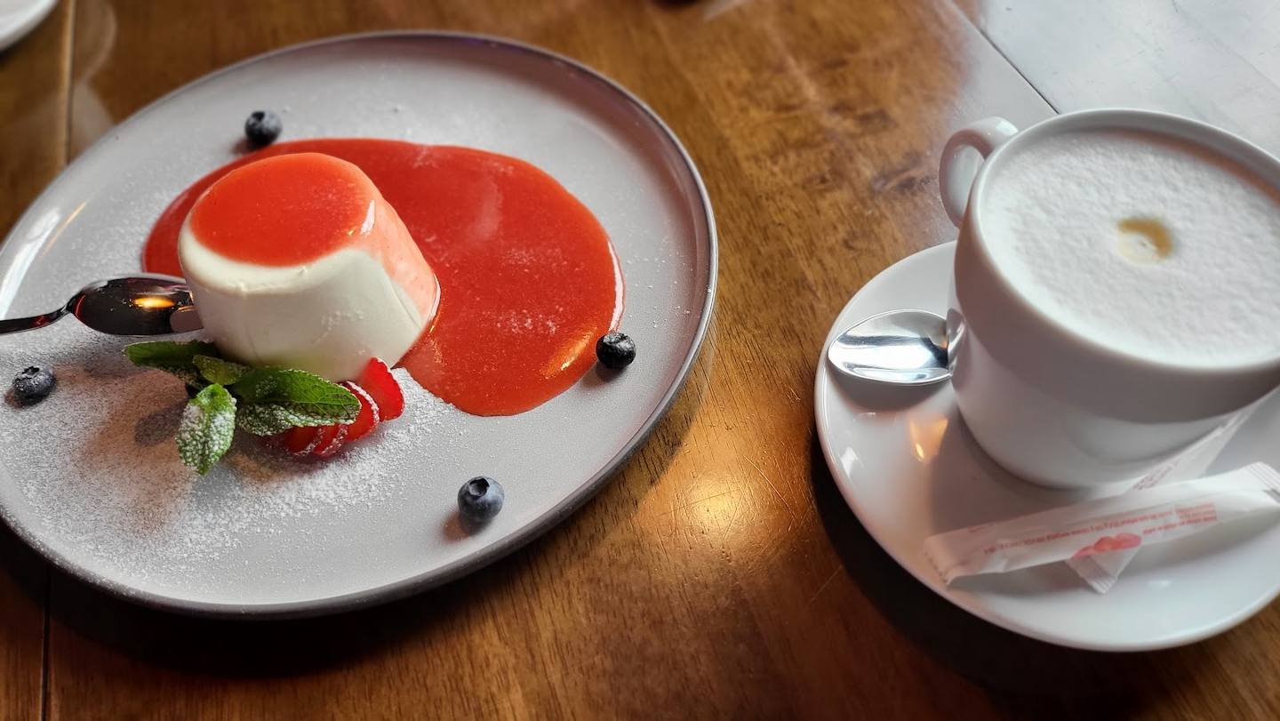 Elegantly plated panna cotta dessert with berry coulis and cappuccino