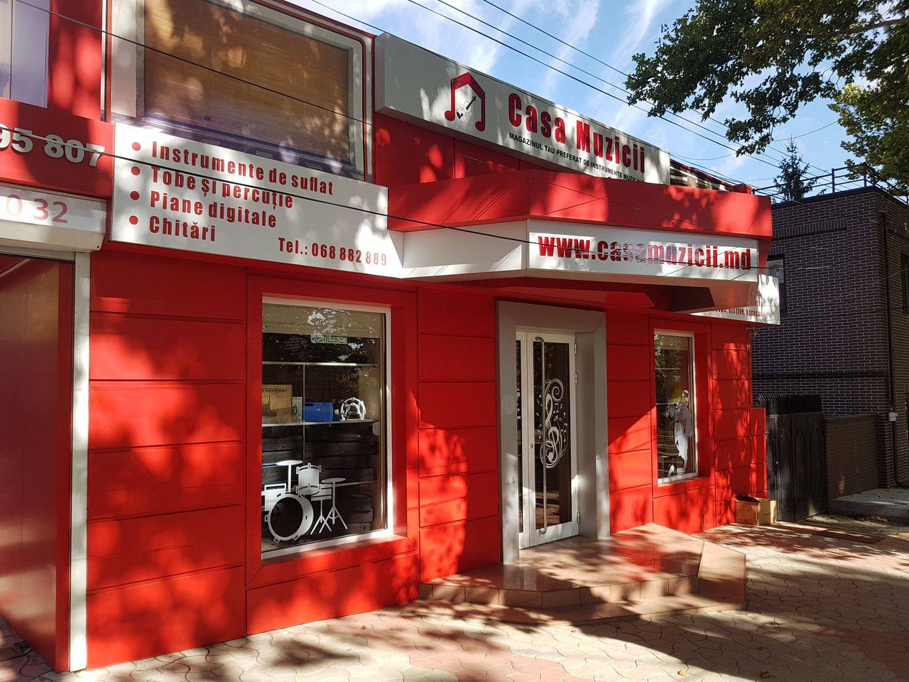 Red storefront facade with signage and glass entrance doors on sunny day