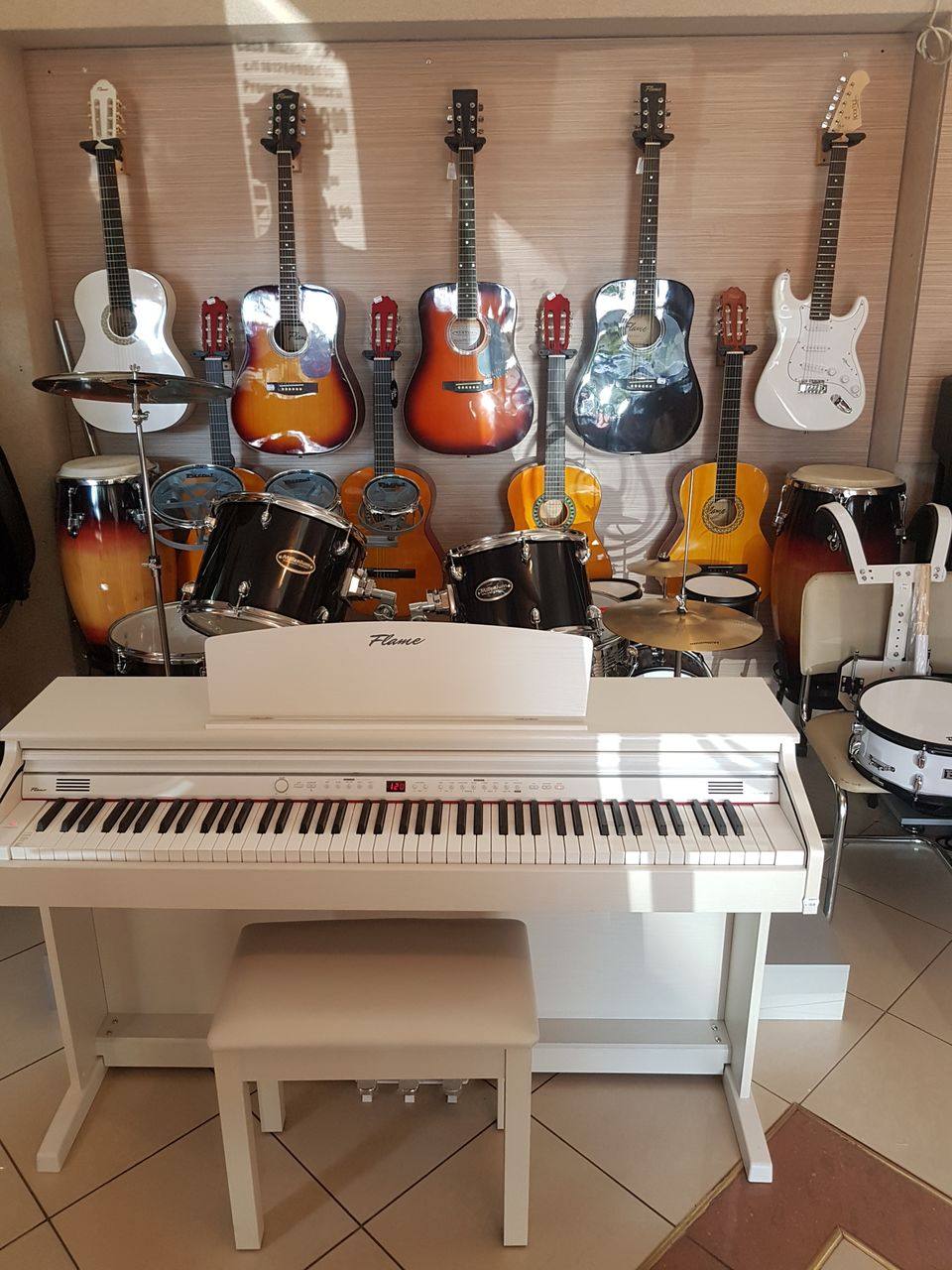 Music school showroom with white digital piano, guitars, and percussion instruments on display