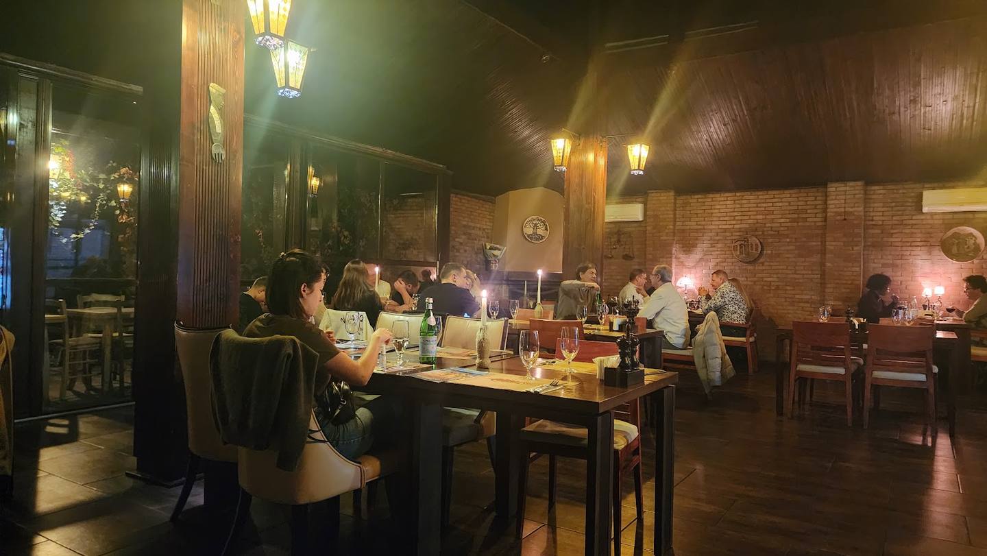 Evening dining room with warm ambient lighting, exposed brick walls, and seated guests at tables