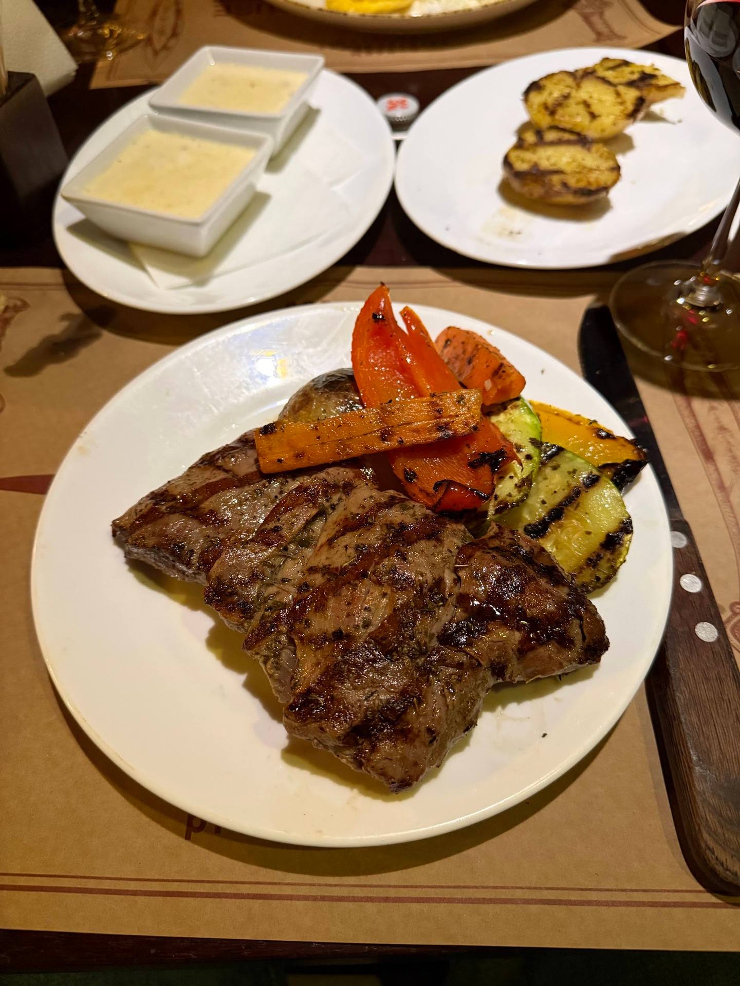 Grilled steak with vegetables and appetizers on white plates