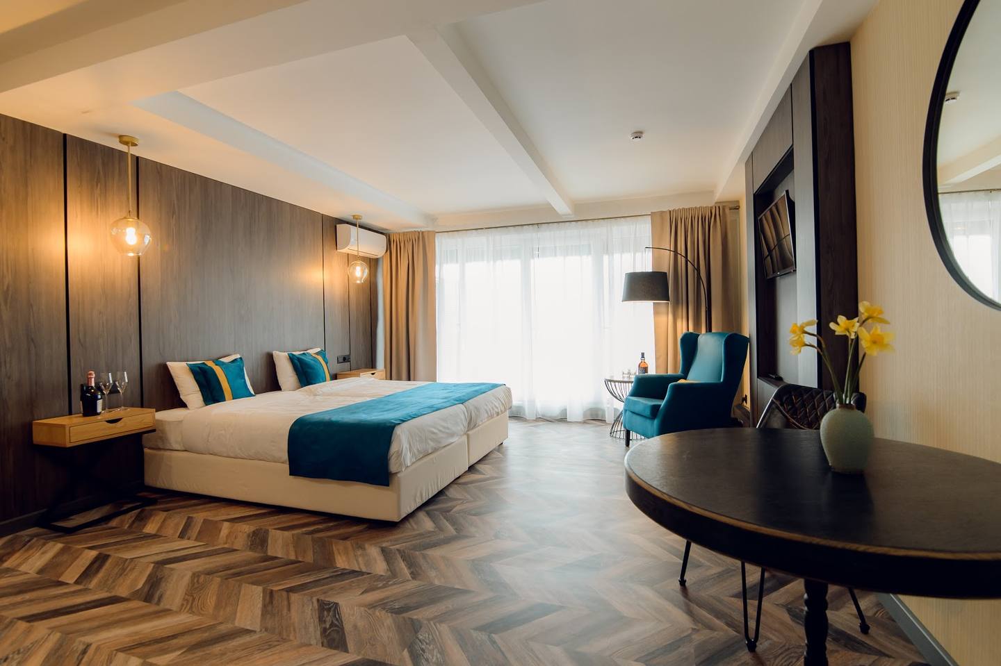 Modern luxury hotel suite with king bed, work desk, and city view windows
