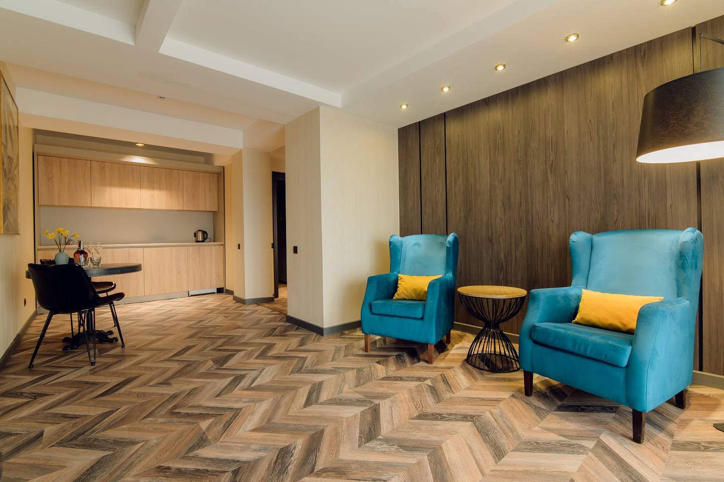 Modern lounge area with geometric flooring, blue armchairs, and contemporary design elements