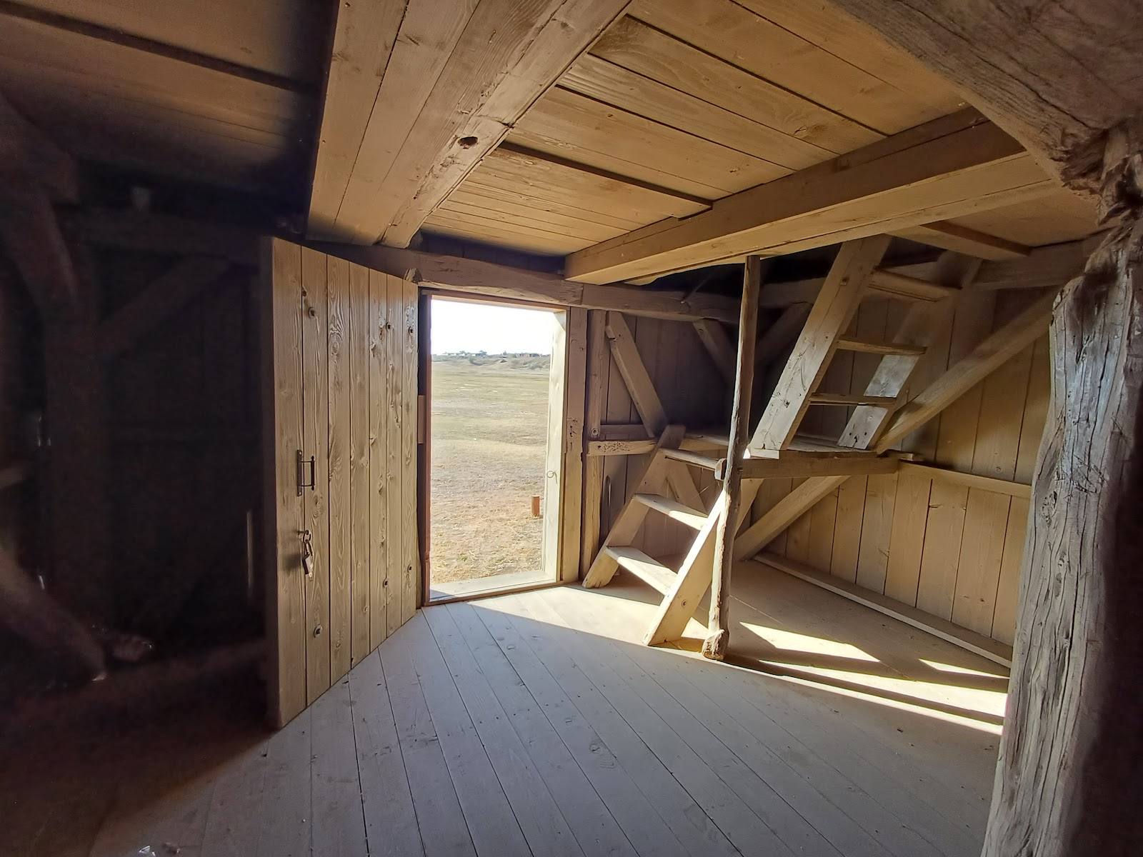 Unfinished wooden interior with open door to rural landscape
