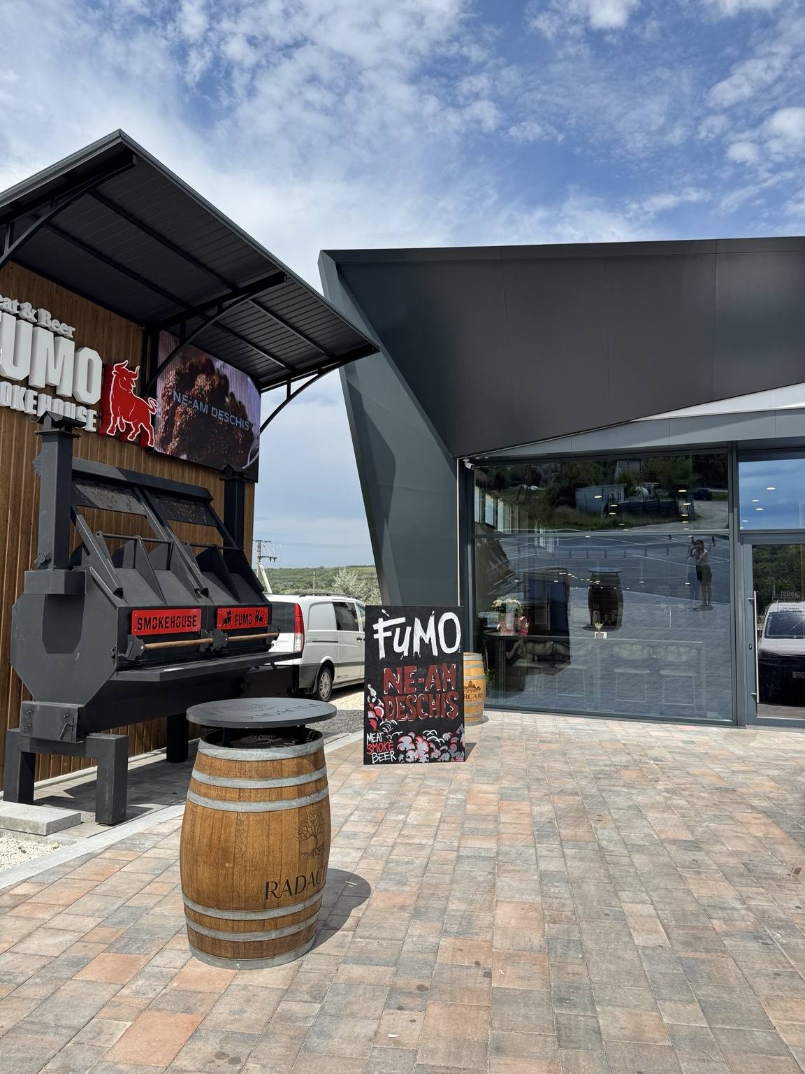 FUMO wine bar exterior with modern black facade and wooden wine barrel decor
