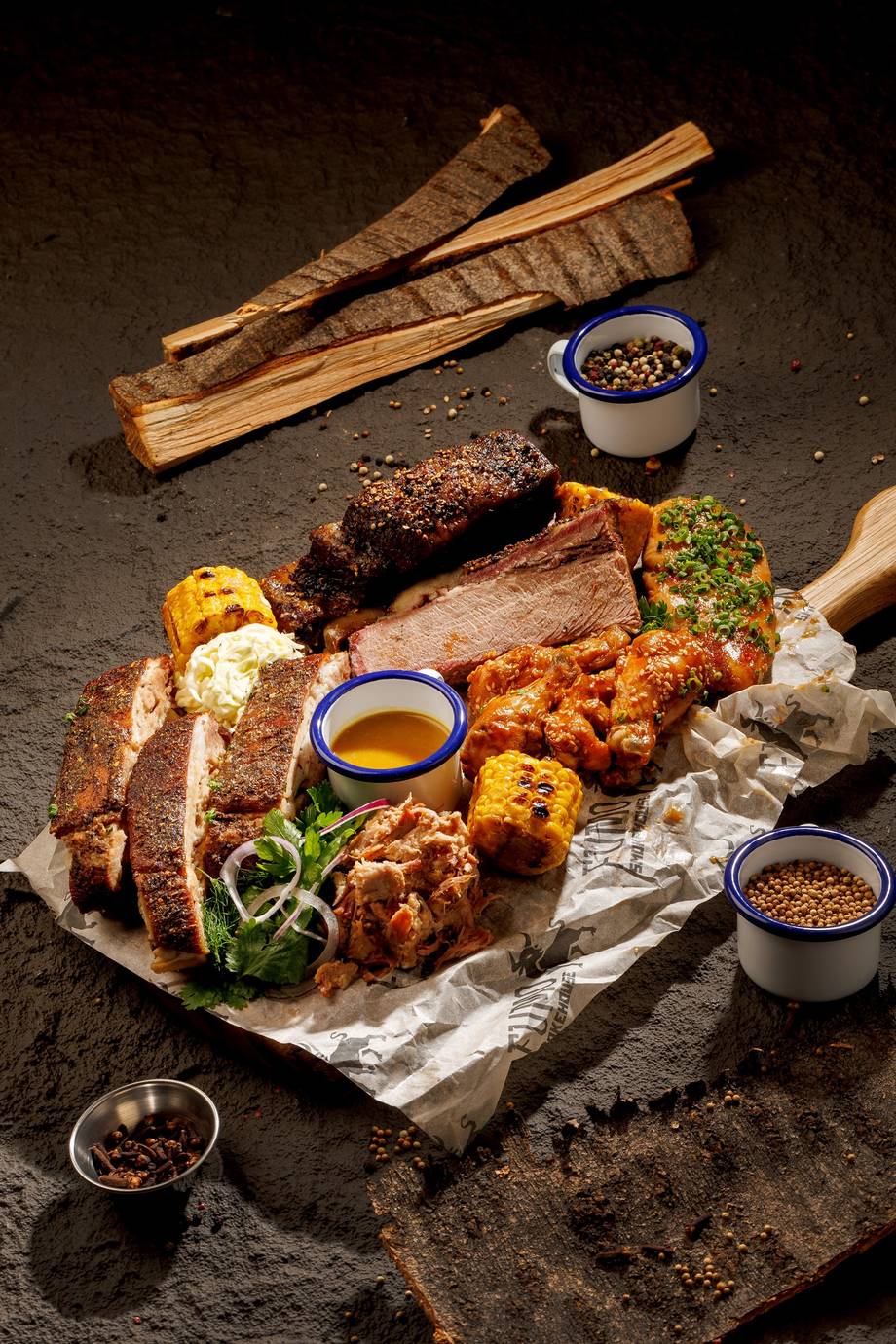 Artfully arranged grilled meats and vegetables with herb oils on dark slate surface