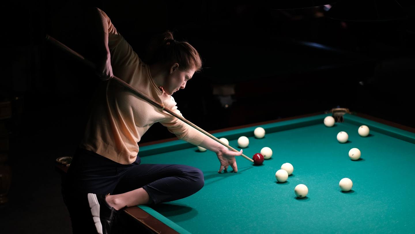 Player taking a shot at the billiards table during a game