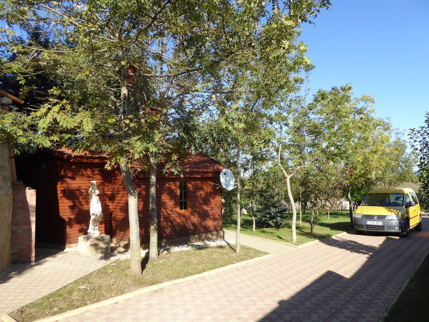 Red brick cottage exterior with brick paving and mature trees on grounds