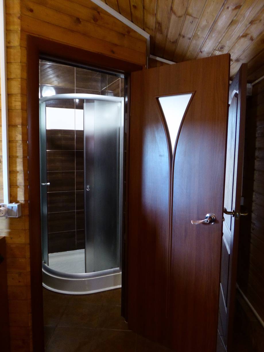 Bathroom with shower stall and dark wood door in rustic lodge interior
