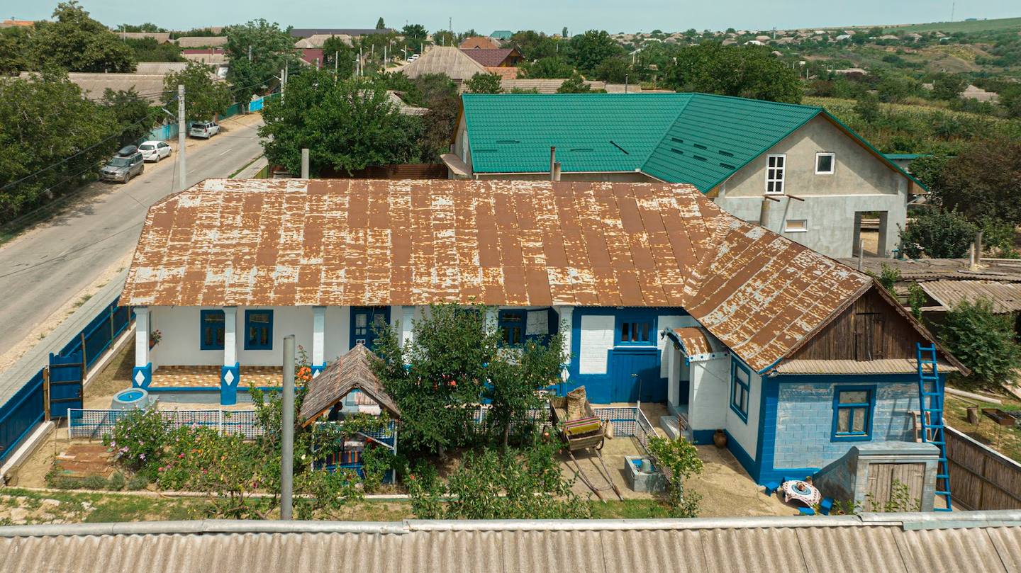 Aerial view of rustic blue building with turquoise roof and surrounding countryside