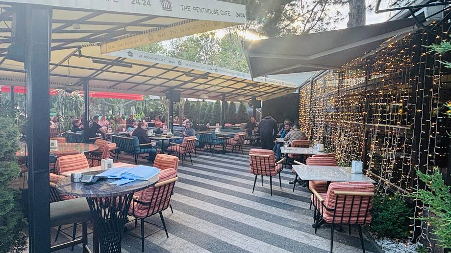 Outdoor terrace with striped paving, modern pergola, and dining area with orange cushioned seating