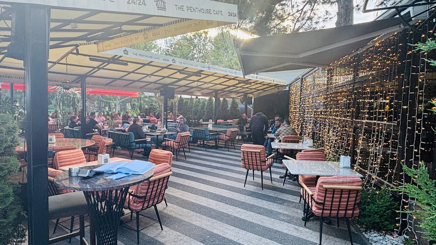 Outdoor terrace with striped paving, modern pergola, and dining area with orange cushioned seating