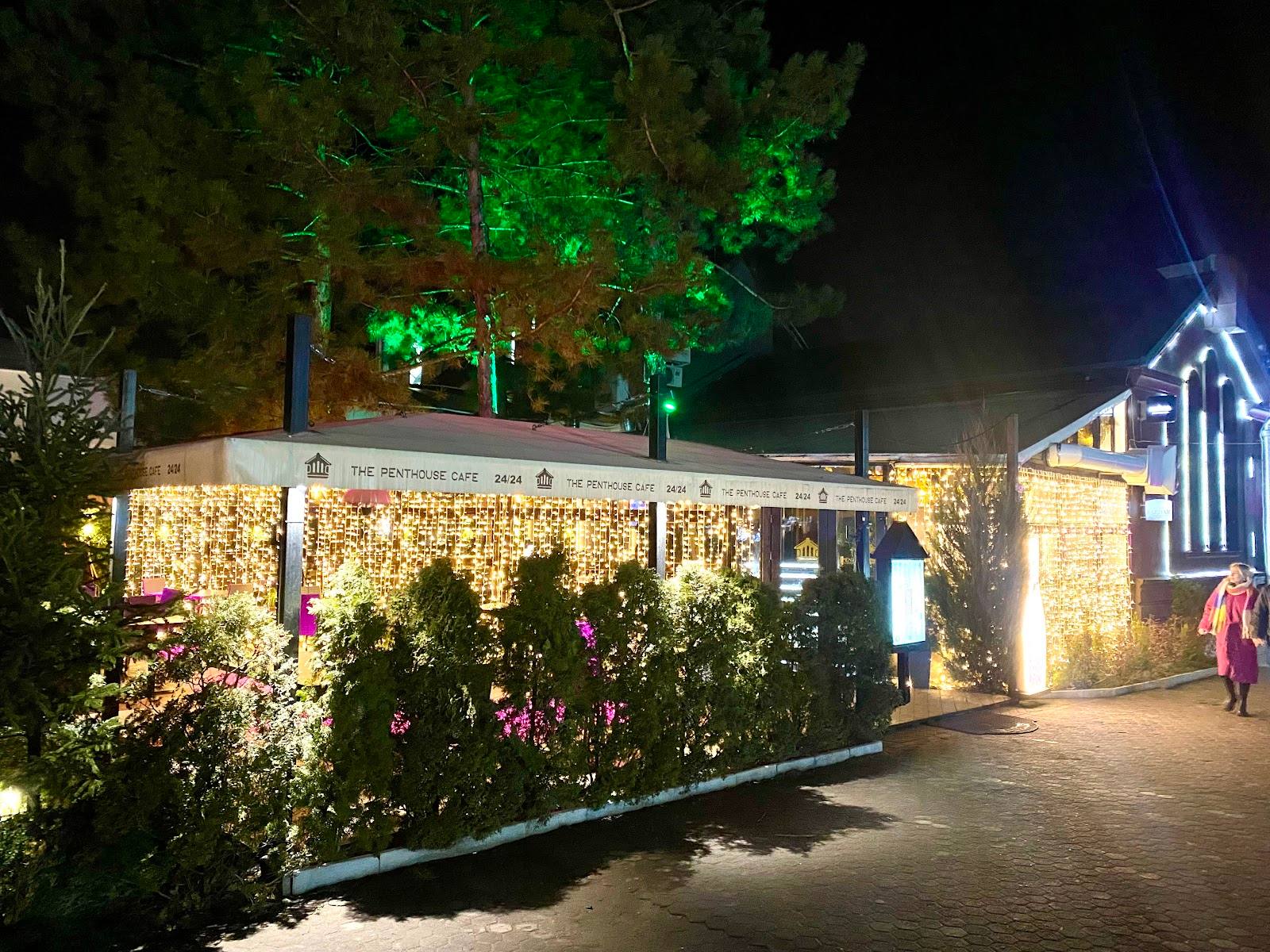 Illuminated outdoor venue with stone walls, lush landscaping, and welcoming entrance at night